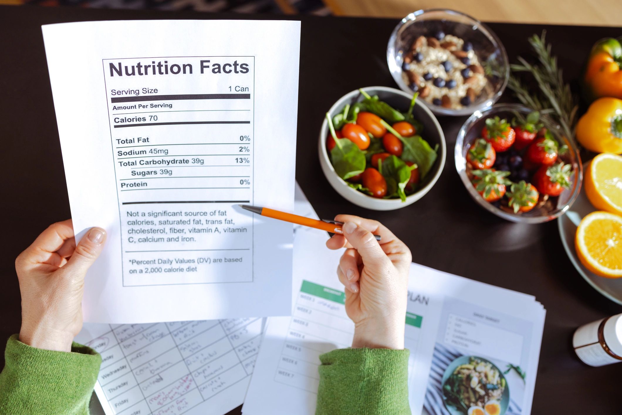 A person holds a nutrition facts sheet, surrounded by healthy foods and meal plans.